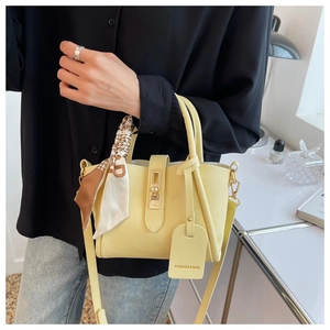 Détail du sac seau jaune avec foulard en soie imprimé et fermoir tournant doré