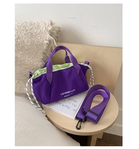 Detail of purple nylon handbag with contrast green lining and adjustable woven strap