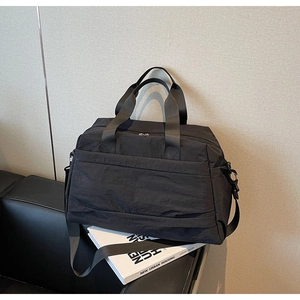 Gros plan d'un grand sac cabas noir en toile avec bandoulière réglable et détails élégants