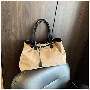 Dettaglio di borsa da viaggio capiente con manici in pelle appesa a una sedia