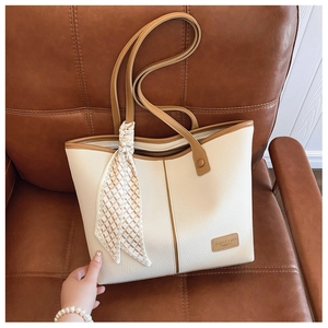 Close-up of cream pebble leather tote bag with brown trim and decorative silk scarf