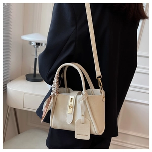 Détail du sac seau en cuir beige avec foulard en soie imprimé sur la poignée