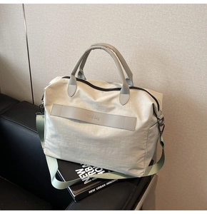 Detail einer grauen Nylon-Reisetasche auf einem Ledersofa mit stilvollen Designbüchern