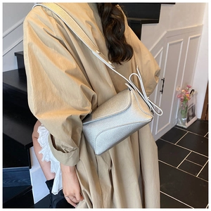 Detailed view of silver metallic crossbody bag with litchi texture on model's shoulder