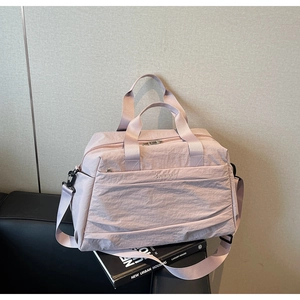 Détail du sac de voyage rose pâle montrant la texture nylon et la bandoulière