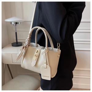 Détail du sac seau crème en cuir grainé avec foulard en soie décoratif sur la poignée