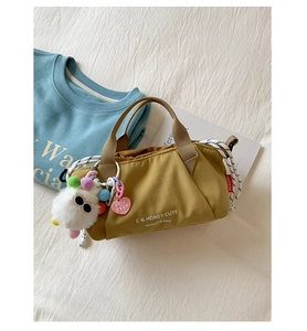 Detail of ginger yellow nylon bag with plush charm and drawstring closure on fabric background