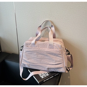 Détail du sac cabas en toile mauve avec fermeture éclair posé sur un canapé en cuir noir