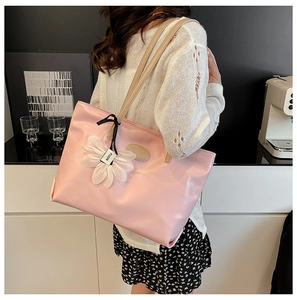 Close-up of light pink leather tote bag featuring a delicate white flower charm detail