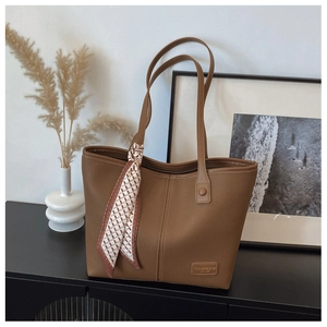 Detail of brown lychee leather tote bag with elegant decorative silk scarf on handle