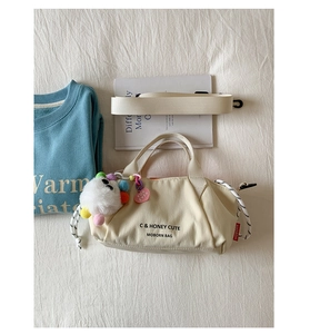 Detail of canvas bag with MOBORN logo tag, plush doll charm, and heart decor