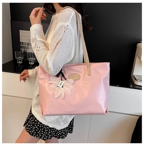 Detail of pink tote bag with textured finish and a white 3D flower decorative pendant