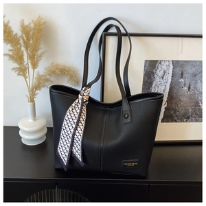 Detail of black tote bag with lychee texture leather and decorative silk scarf accessory