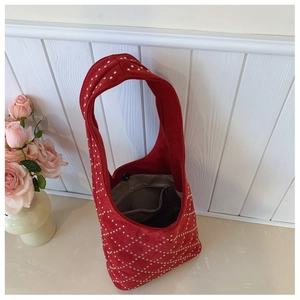 Detail of red suede hobo bag with silver rivet studs and interior zipper pocket
