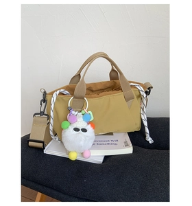 Detail of khaki fabric crossbody bag with drawstring closure and colorful monster charm