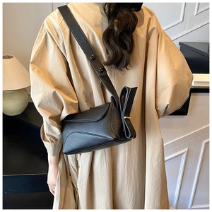 Detail of black lychee grain leather crossbody bag featuring a unique side bow design