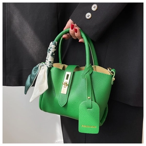 Détail du sac seau en cuir grainé vert avec poignée en soie et fermoir métallique