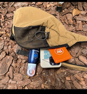 Detail of khaki nylon chest bag showing storage capacity with phone and sunscreen items