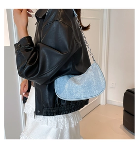 Detail of light blue sequined crescent bag with silver chain strap on model shoulder