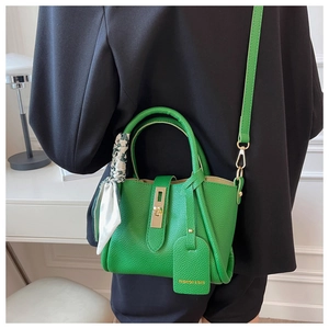 Détail du sac seau en cuir grainé vert avec fermoir doré et décoration de foulard