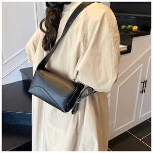 Detail of black pebbled leather crossbody bag featuring a unique side knot and flap design