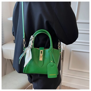 Détail du sac seau en cuir vert avec foulard en soie imprimé et fermoir doré
