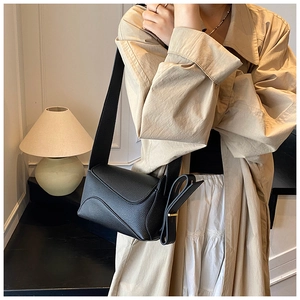 Detail of black pebble leather crossbody bag with wave flap and knot shoulder strap
