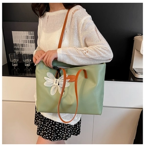Mint green tote bag detail showing daisy charm and brown leather shoulder straps
