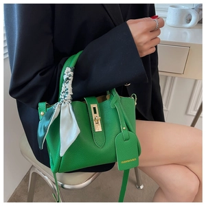 Détail du sac seau en cuir grainé vert vif avec foulard en soie fleuri sur l'anse