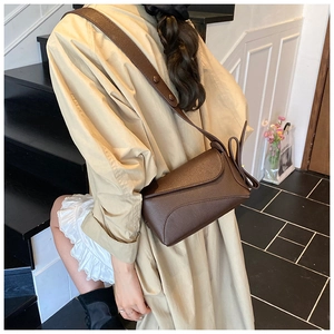Detail of dark brown crossbody bag with litchi grain texture and elegant side knot
