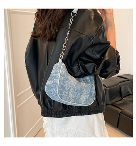 Detail of light blue denim crescent bag featuring silver chain strap and leather piping
