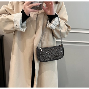 Close-up of black denim handbag featuring sparkling rhinestones and silver chain strap