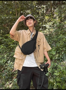 Outdoor close-up of a black oxford fabric crossbody bag styled with cargo hiking apparel