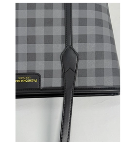 Close-up of checkered fabric texture and leather brand tag on a large tote bag