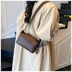 Detail of dark brown lychee textured leather shoulder bag with asymmetrical flap