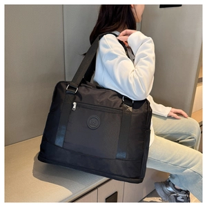 Close-up of a large black waterproof Oxford travel bag held by a model in a minimal setting