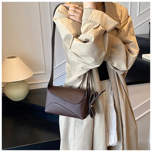 Detail of dark brown lychee grain leather shoulder bag with decorative side bow accents