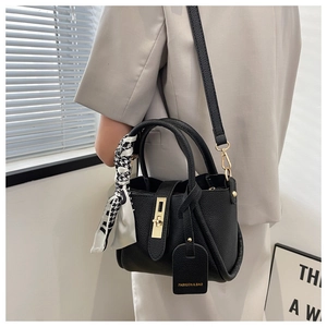 Détail du sac seau noir en cuir grainé avec fermoir doré et foulard pied-de-poule