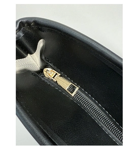 Macro view of gold metal zipper detail and herringbone lining in a black leather tote
