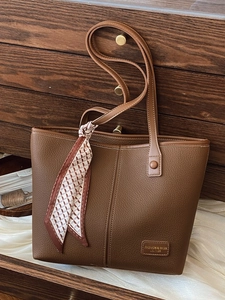 Chic brown litchi leather tote bag with geometric silk scarf on retro background