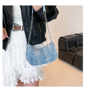 Detail of light blue denim hobo bag with silver chain strap and leather trim
