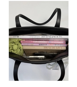 Spacious interior of a black leather tote bag holding a folding umbrella and magazines