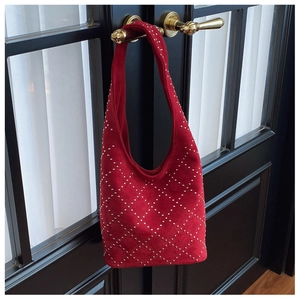 Dettaglio borsa hobo rossa con borchie argentate appesa a porta nera d'epoca