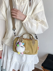 Minimalist ginger yellow nylon crossbody bag with plush charm and woven drawstring detail