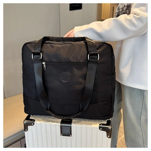Close-up of black waterproof travel bag with logo secured on a white striped suitcase