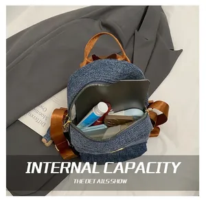 Dettaglio dello zaino in denim blu con ampio interno per tablet e oggetti quotidiani