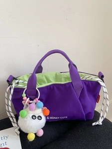 Purple nylon crossbody bag with drawstring closure and colorful pompom accessory