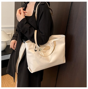 Close-up of a cream tote bag with contrast brown handles and a white flower charm
