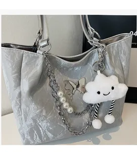 Dettaglio borsa tote argento con texture a onde, catena metallica e ciondolo a nuvola
