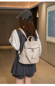 Detail of beige PU leather backpack featuring long decorative tassels and side pockets